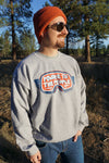 Person wearing a gray sweatshirt with a logo and text outdoors