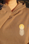 Brown hoodie with a white leaf design on a blurred background