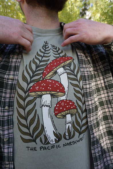 Person wearing a t-shirt with a mushroom design and text 'The Pacific Northwest'.