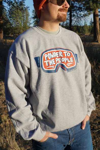 Person wearing a gray sweatshirt with 'Powder to the People' graphic in a forest setting