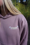 Person wearing a purple hoodie with 'Wayward & Wild' logo outdoors