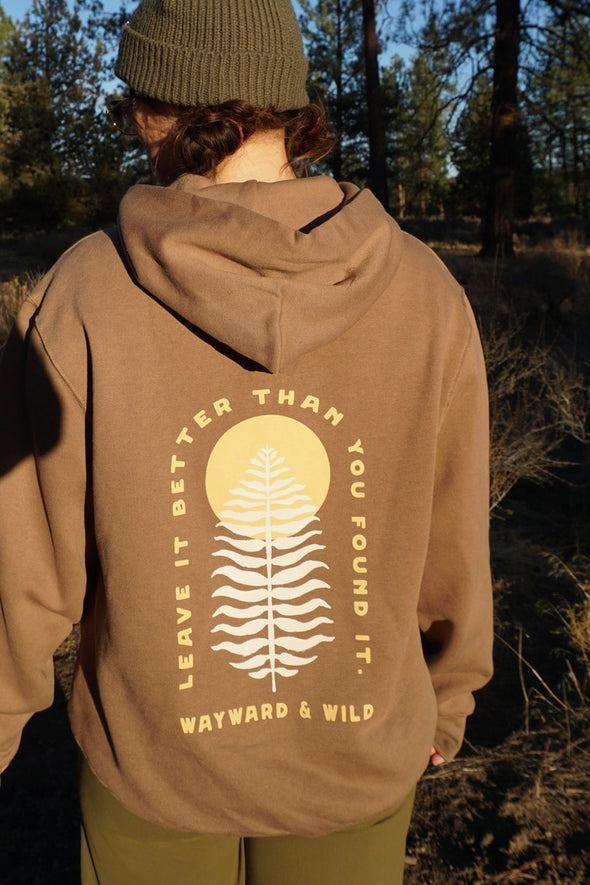 Person wearing a brown hoodie with a nature-themed design in a forest setting