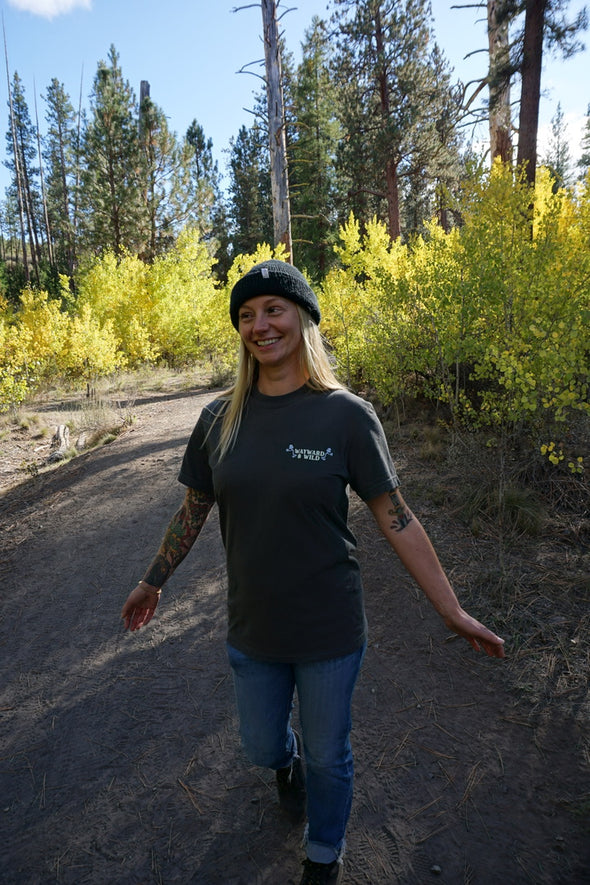 Person walking on a dirt path with trees and yellow bushes in the background
