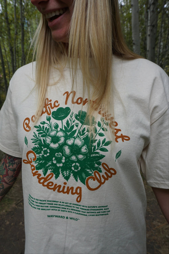 Person wearing a t-shirt with 'Pacific Northwest Gardening Club' design outdoors.