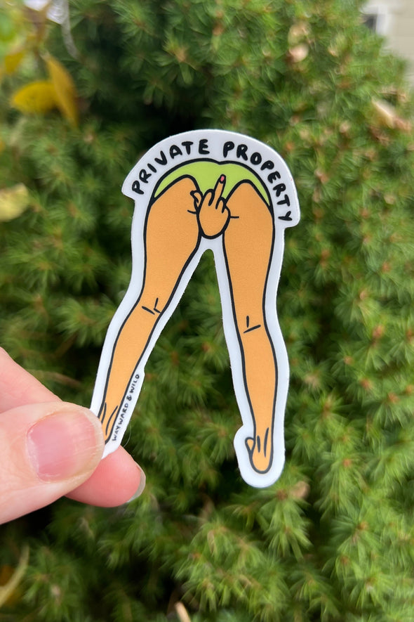 Sticker of a cartoonish depiction of legs with 'Private Property' text held in front of a green bush.