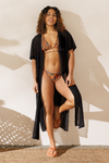 Woman in a bikini and cover-up standing against a light background