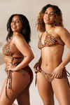 Two women wearing patterned bikinis against a neutral background