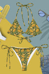 Green bikini set with lemon pattern on a yellow and blue background with sunglasses and lemon slices.
