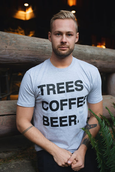 Photo of a guy wearing the light gray TREES COFFEE BEER T-Shirt with a little pine tree next to "BEER" standing in front of a lodge at Silver Falls State Park in Oregon.